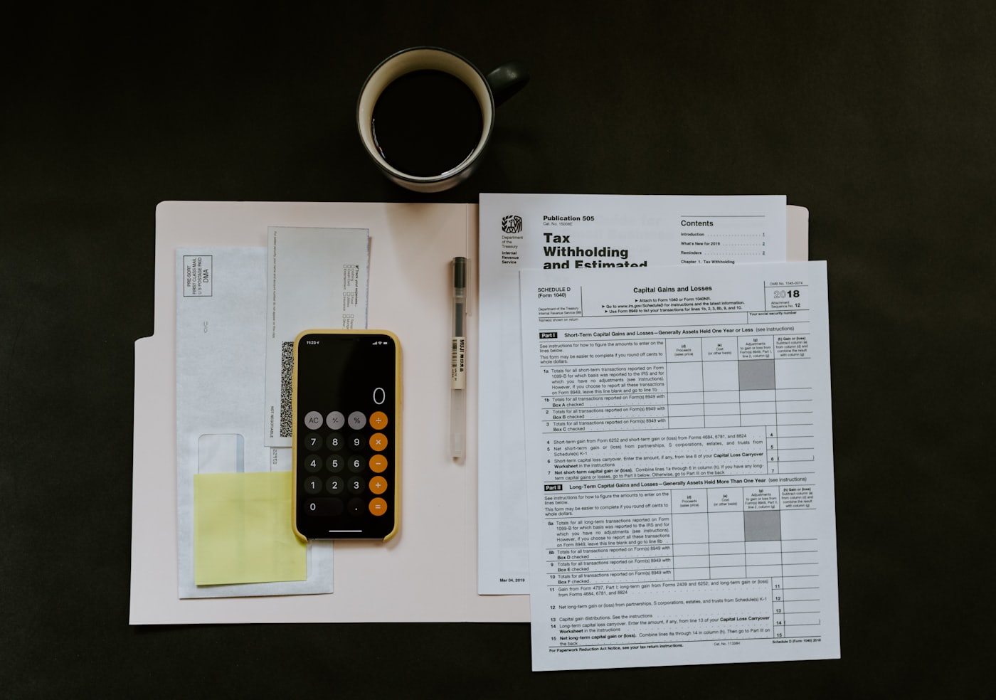 W-2 and 1099 tax forms on a desk with a calculator and coffee mug